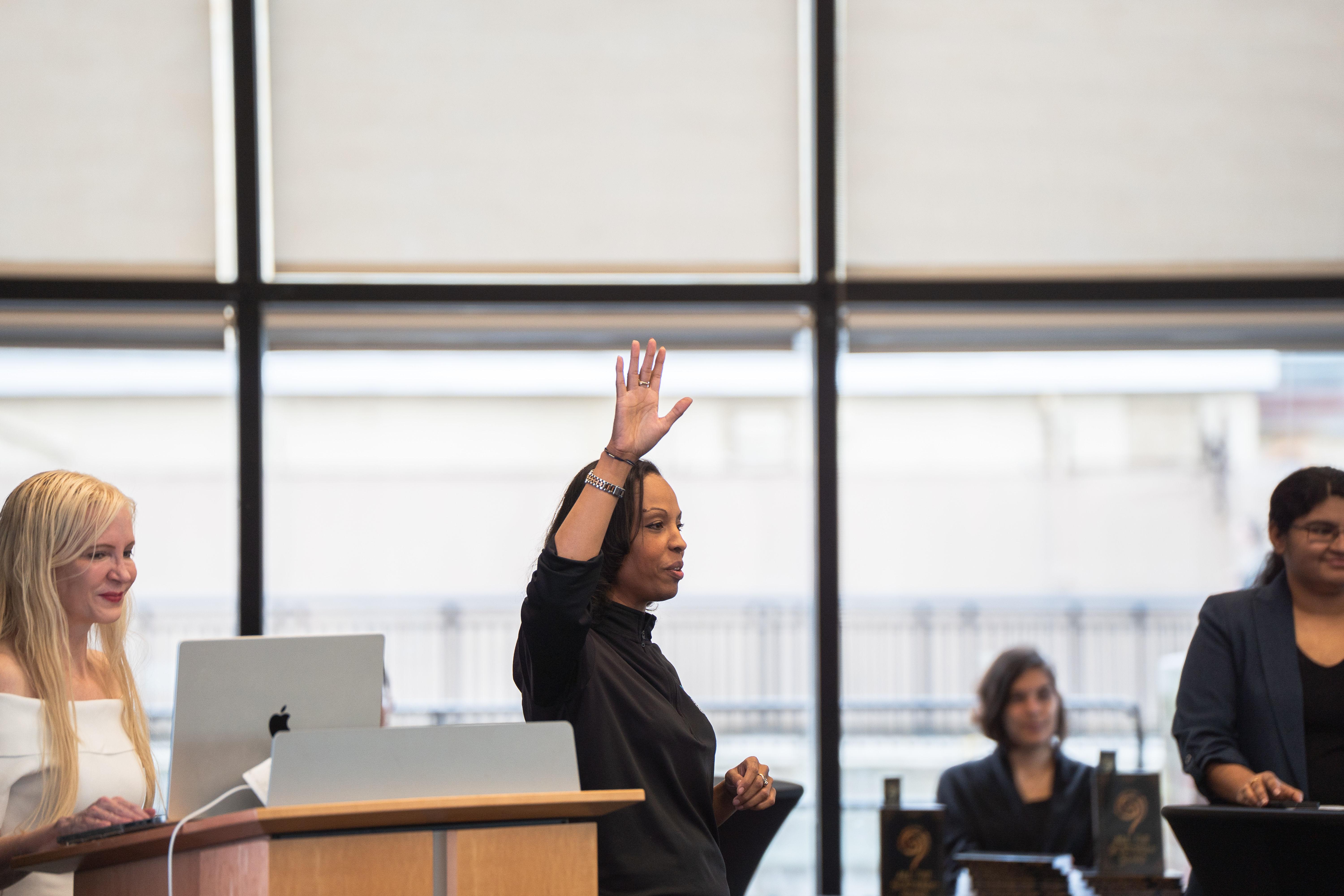 Dr. Circe Gray Le Compte at the podium beside Dr. Candice D. Carpenter, who is mid-gesture with her hand raised, and Attrayee Chakraborty at right.