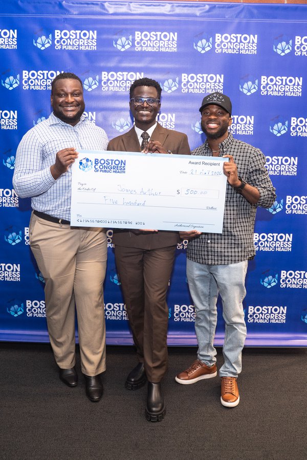 James Arthur in the center, flanked by two friends, the three of them holding the oversized $500 BCPH check together in front of the backdrop.