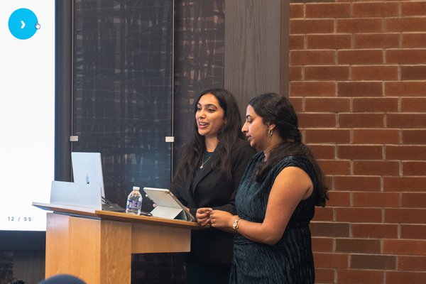 Shriya Veluri and Nanditha Niranjan presenting at the podium, partner team out of UT Health Houston.