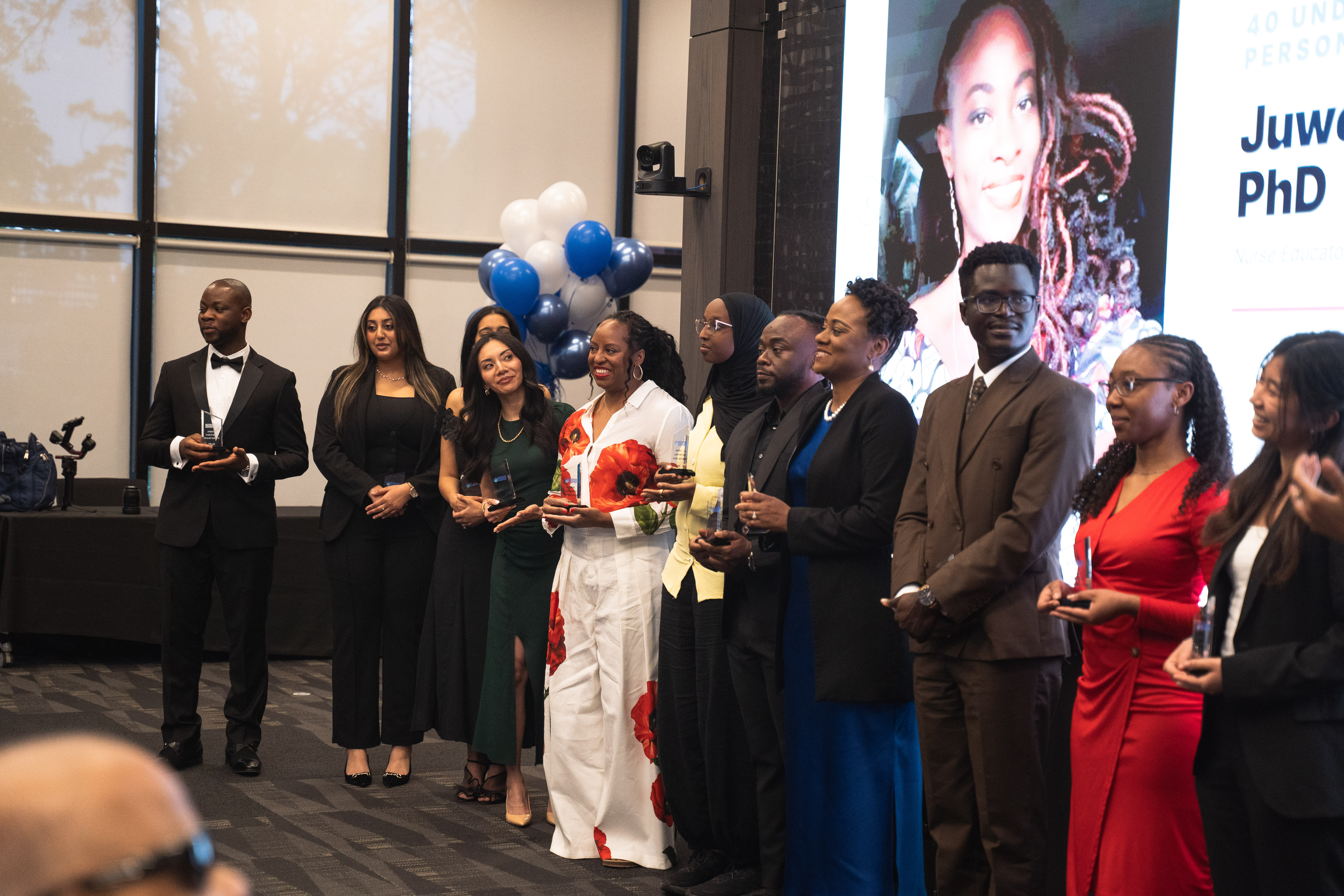 40 Under 40 honorees together in front of the projection screen.