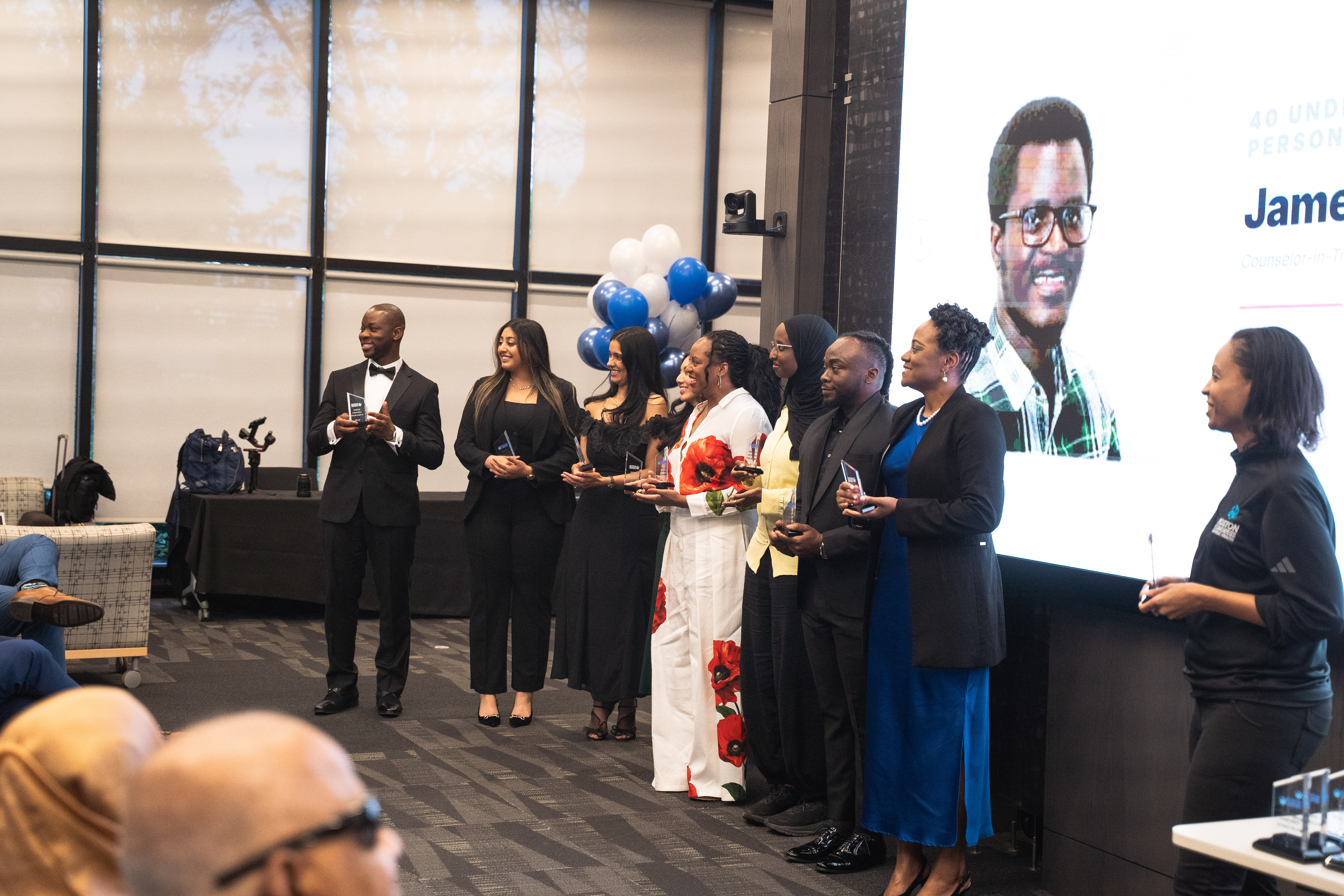 40 Under 40 honorees gathered together holding their trophies.